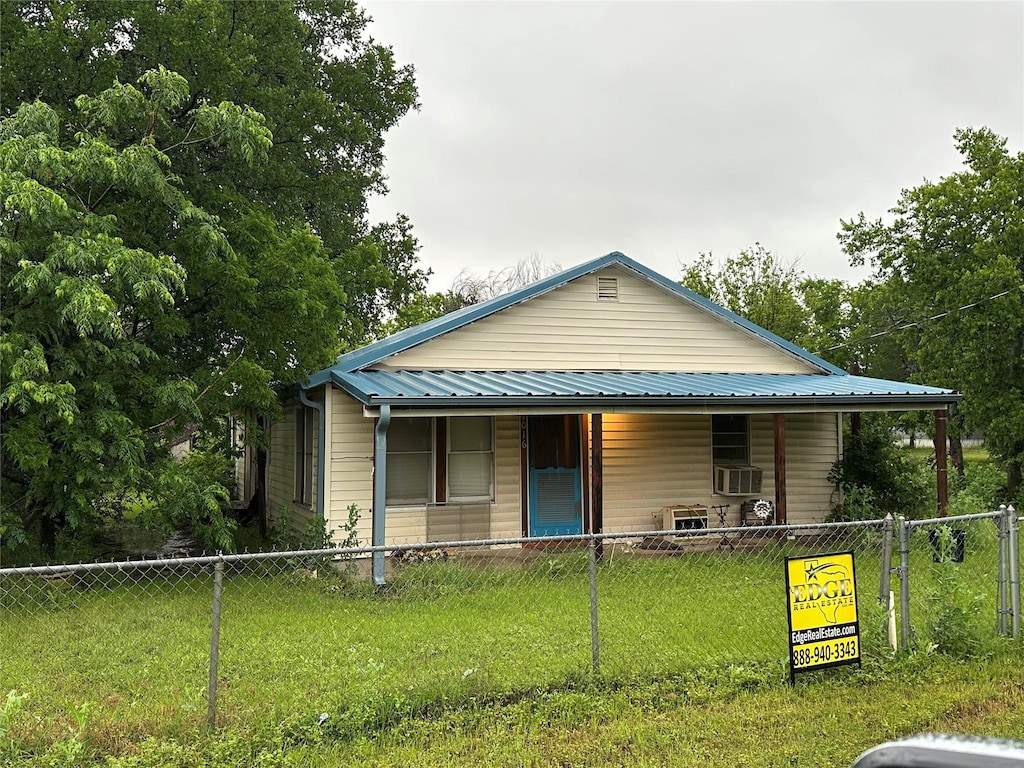 view of front of property with covered porch, fence private yard, a front lawn, and cooling unit