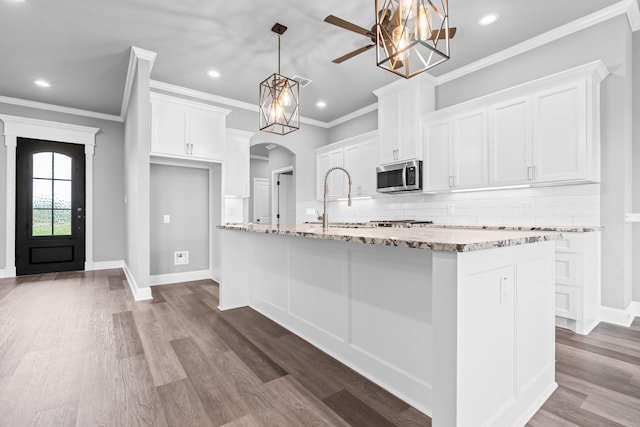 120 Water View Ln, Robinson, TX 76706 - kitchen with stainless steel microwave, white cabinetry, arched walkways, and tasteful backsplash