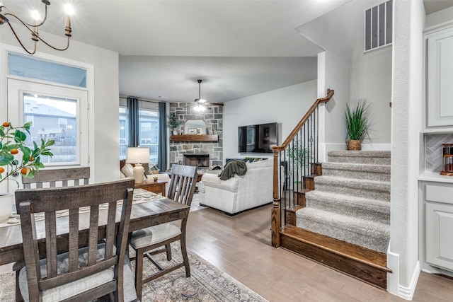 2009 Gill Star Dr, Haslet, TX 76052 - dining space featuring light wood finished floors, stairway, visible vents, a stone fireplace, and a chandelier