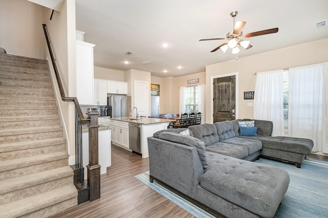 living area with ceiling fan, stairway, light wood-style floors, and recessed lighting
