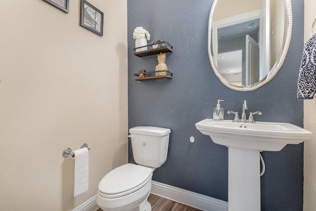 half bath featuring toilet, wood finished floors, and baseboards