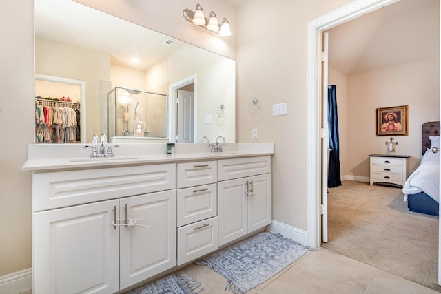 bathroom with a stall shower, double vanity, a spacious closet, baseboards, and tile patterned flooring