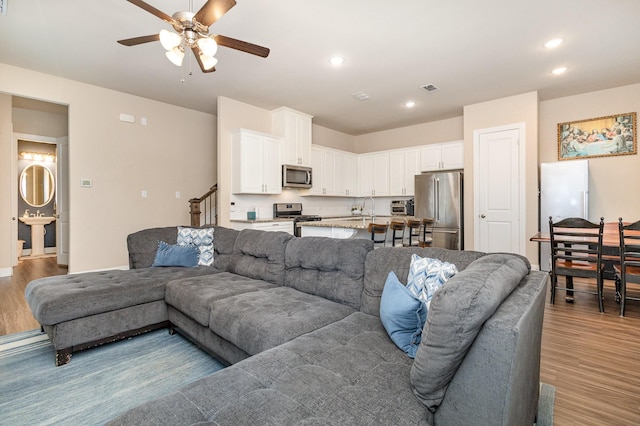 living room with ceiling fan, light wood-style flooring, and recessed lighting