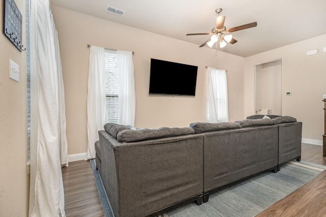living area featuring wood finished floors, a ceiling fan, and baseboards