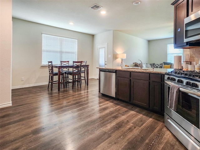 601 Bassett Hall Rd, Fate, TX 75189 - kitchen with dark brown cabinets, dark wood-style flooring, visible vents, a peninsula, and stainless steel appliances