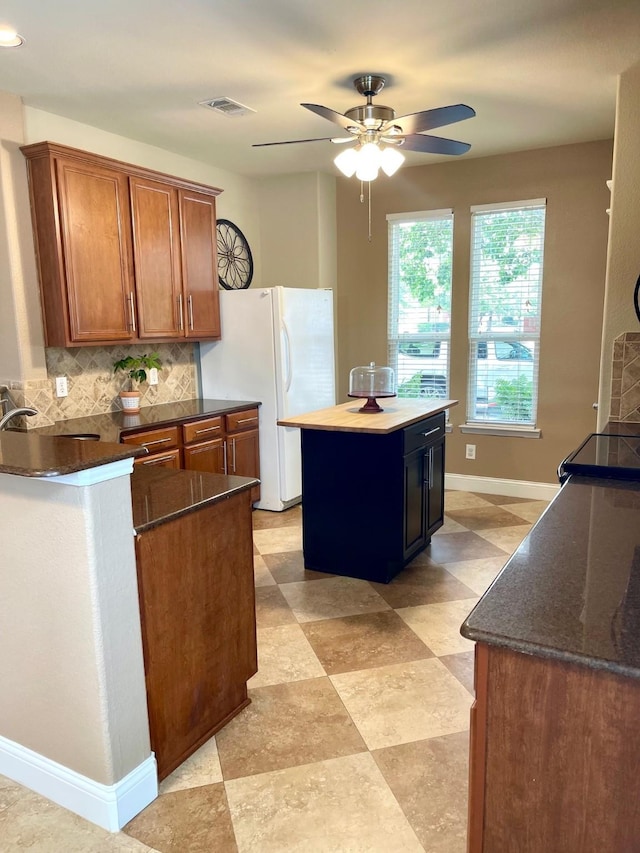 7125 Cotton Seed Dr, Mckinney, TX 75070 - kitchen featuring backsplash, baseboards, ceiling fan, brown cabinets, and freestanding refrigerator