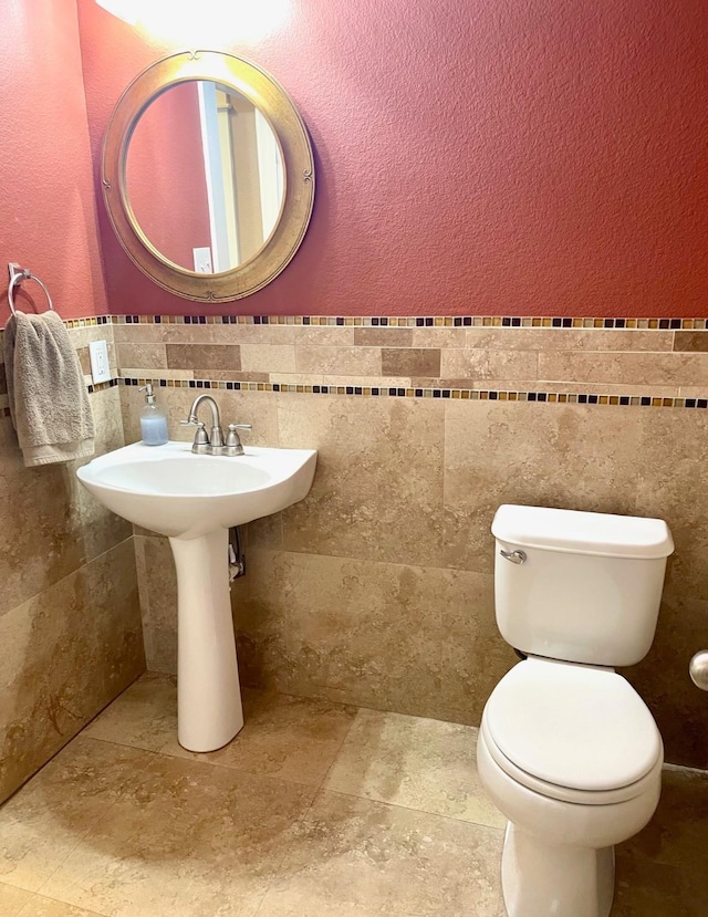 7125 Cotton Seed Dr, Mckinney, TX 75070 - bathroom with tile walls, toilet, a textured wall, and wainscoting