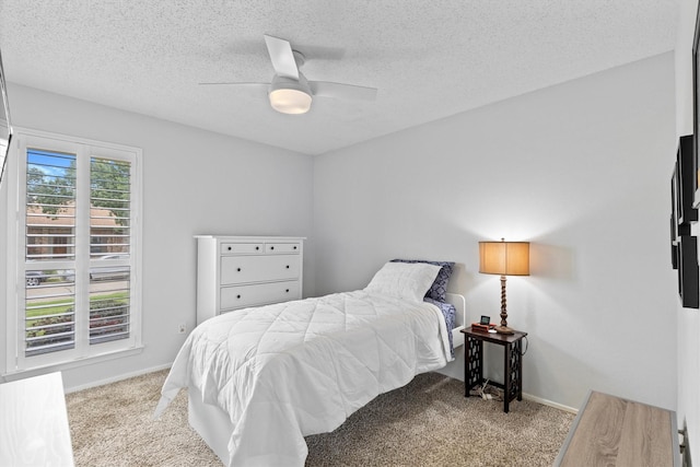 carpeted bedroom with a textured ceiling, ceiling fan, and baseboards