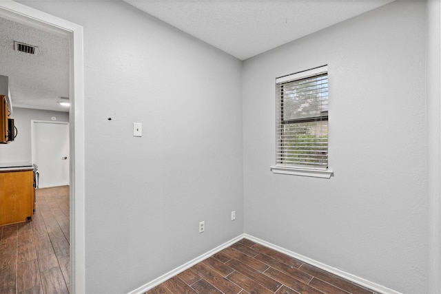 empty room with dark wood-type flooring, baseboards, and a textured ceiling
