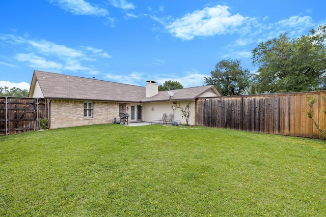 rear view of house featuring a patio, a chimney, and brick siding