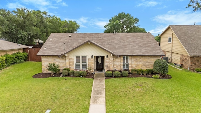 view of front of property with a shingled roof, brick siding, and a front lawn