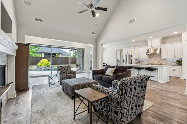 living area featuring ceiling fan, high vaulted ceiling, light wood-style floors, recessed lighting, and a fireplace
