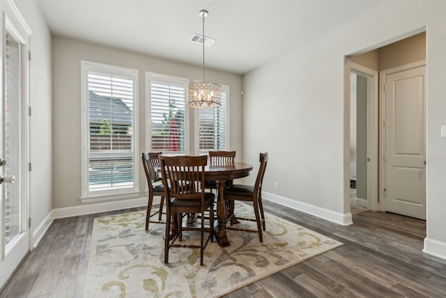 dining area featuring a chandelier, wood finished floors, and baseboards