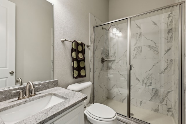 full bathroom with a marble finish shower, toilet, a textured wall, and vanity