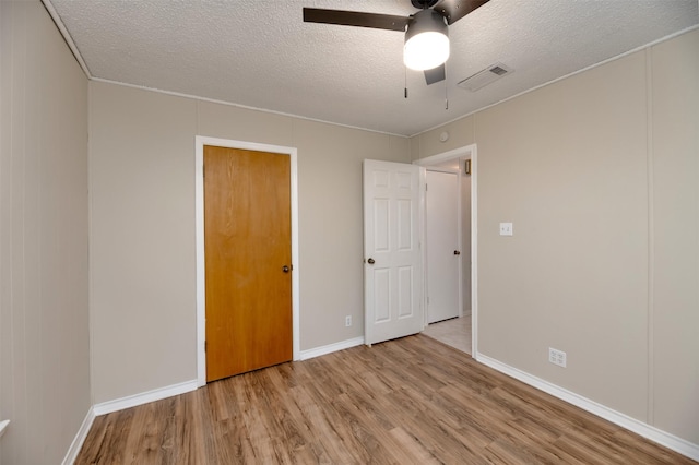 unfurnished bedroom featuring wood finished floors, a textured ceiling, baseboards, and a ceiling fan
