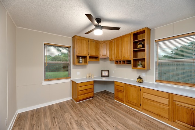 kitchen with open shelves, light wood finished floors, ceiling fan, light countertops, and a textured ceiling