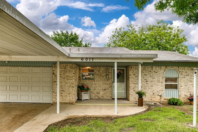 property entrance featuring a garage, brick siding, concrete driveway, and a shingled roof