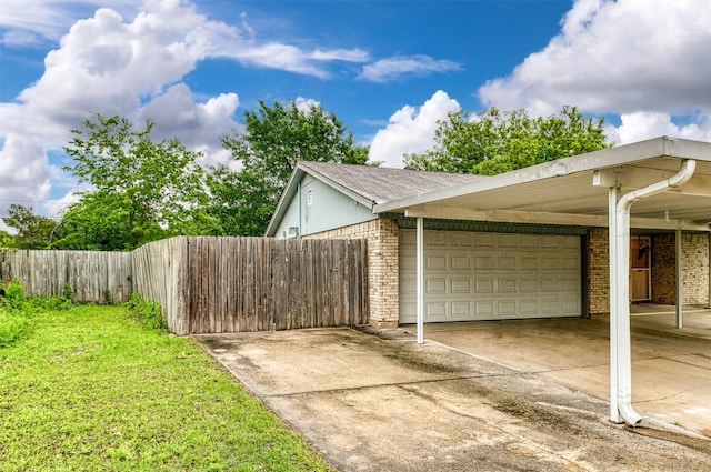 view of home's exterior with a garage, driveway, brick siding, and fence
