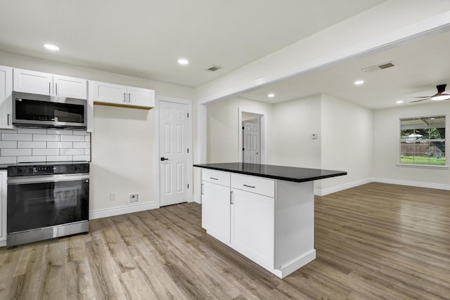 1110 Green St, Abilene, TX 79603 - kitchen with stainless steel microwave, electric stove, light wood finished floors, white cabinets, and recessed lighting