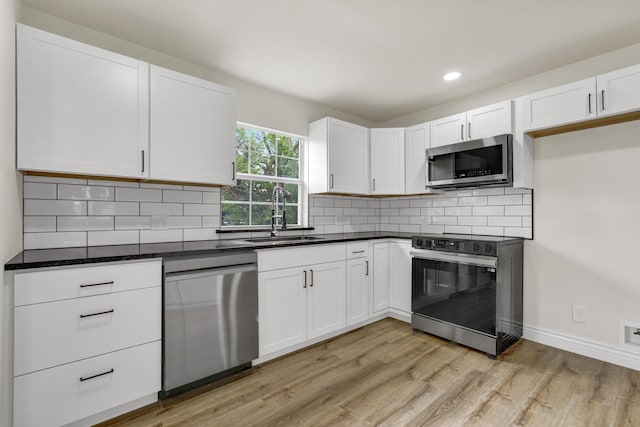1110 Green St, Abilene, TX 79603 - kitchen with stainless steel appliances, a sink, light wood-style flooring, white cabinets, and backsplash
