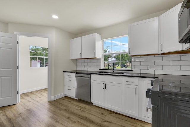1110 Green St, Abilene, TX 79603 - kitchen with dishwasher, a sink, tasteful backsplash, dark countertops, and light wood-style floors