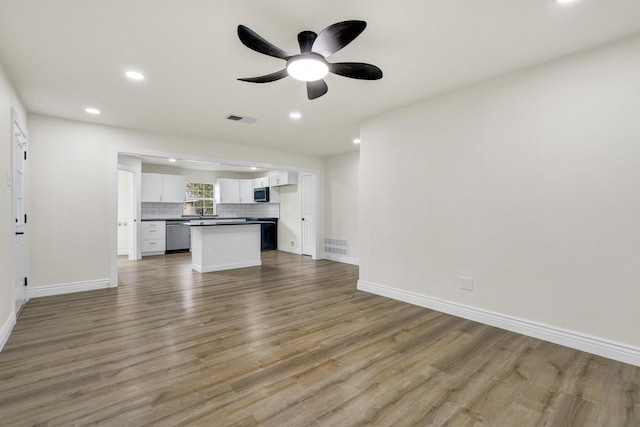 1110 Green St, Abilene, TX 79603 - unfurnished living room featuring wood finished floors, recessed lighting, baseboards, ceiling fan, and a sink