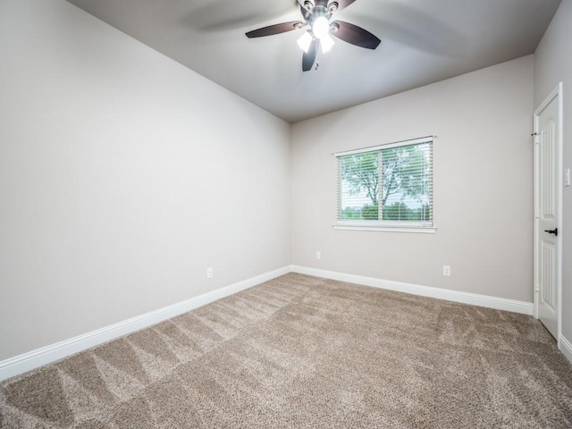 carpeted spare room with a ceiling fan and baseboards