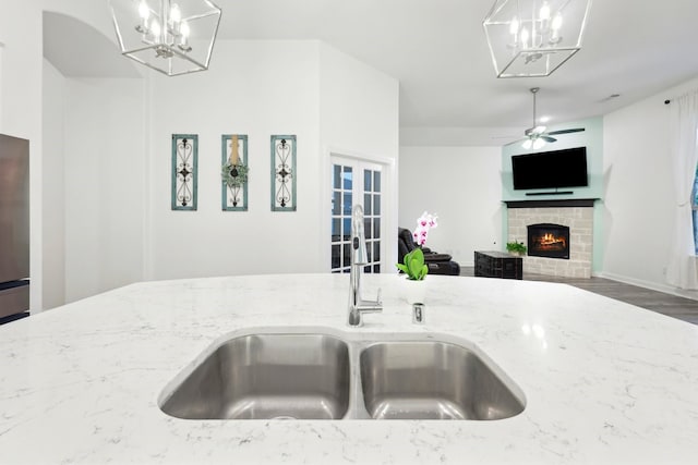 1405 Chickadee Dr, Argyle, TX 76226 - kitchen with a chandelier, light stone counters, a warm lit fireplace, and ceiling fan