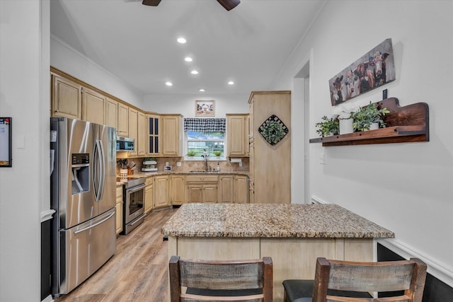 kitchen featuring stainless steel appliances, light brown cabinetry, a sink, light wood-type flooring, and light stone counters