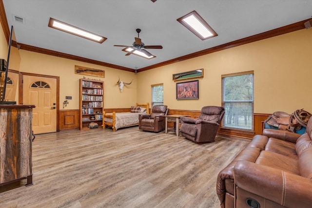 living area featuring a wainscoted wall, wood finished floors, plenty of natural light, ornamental molding, and a ceiling fan