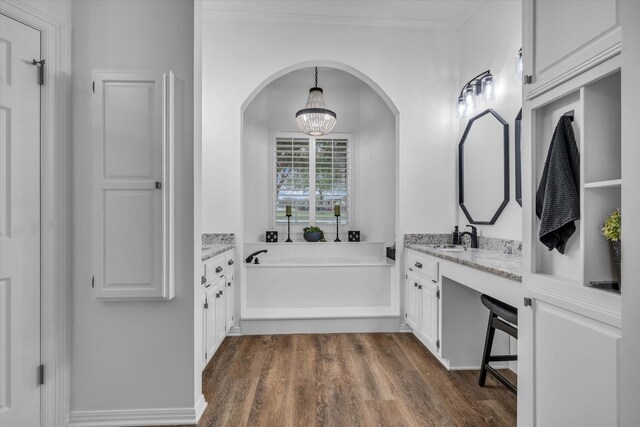 full bath featuring wood finished floors, a chandelier, vanity, and a garden tub