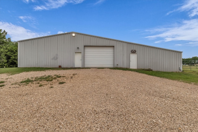 view of outbuilding featuring dirt driveway, an outbuilding, and fence
