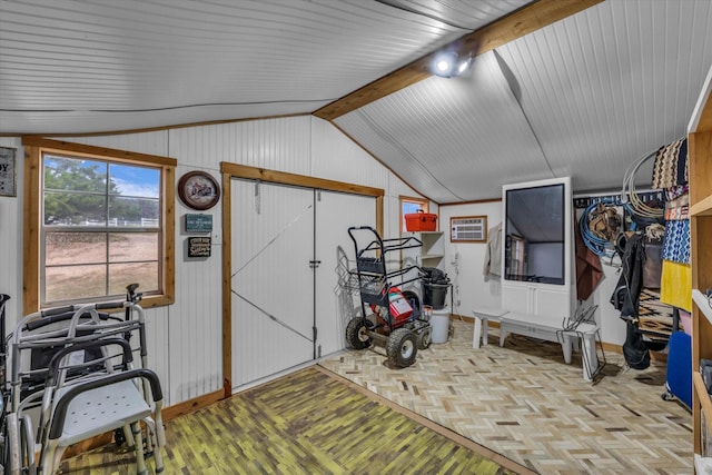interior space with vaulted ceiling, wooden walls, parquet flooring, and baseboards