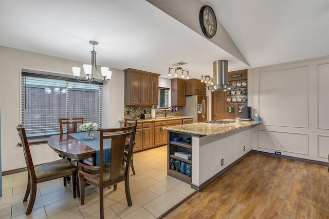 kitchen with a chandelier, stainless steel appliances, island range hood, open shelves, and a peninsula
