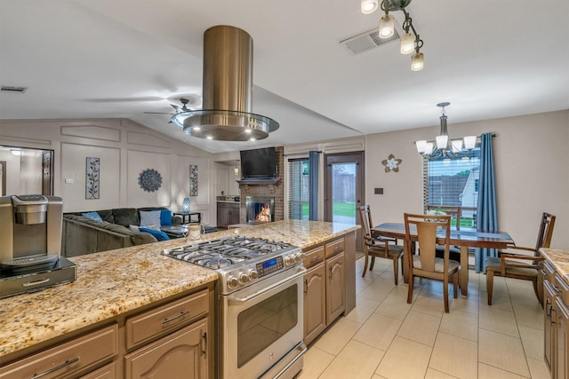 kitchen with gas range, open floor plan, light tile patterned floors, a chandelier, and a fireplace