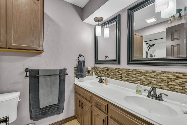 bathroom featuring toilet, double vanity, tasteful backsplash, and a shower