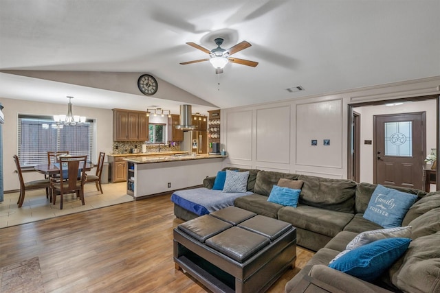 living area with lofted ceiling, ceiling fan, a chandelier, and light wood-type flooring