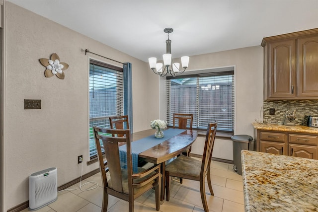 dining room with a chandelier, light tile patterned flooring, and baseboards