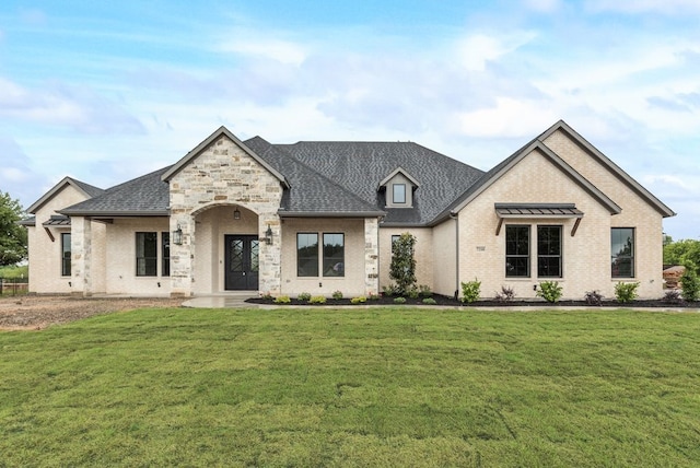french country home featuring brick siding, a front yard, and roof with shingles