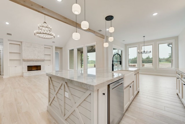 kitchen with a chandelier, stainless steel dishwasher, a sink, light wood finished floors, and healthy amount of natural light