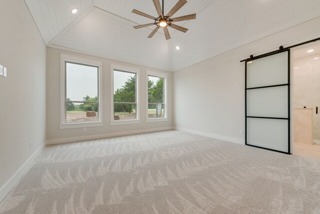carpeted spare room with a barn door, ceiling fan, vaulted ceiling, baseboards, and recessed lighting