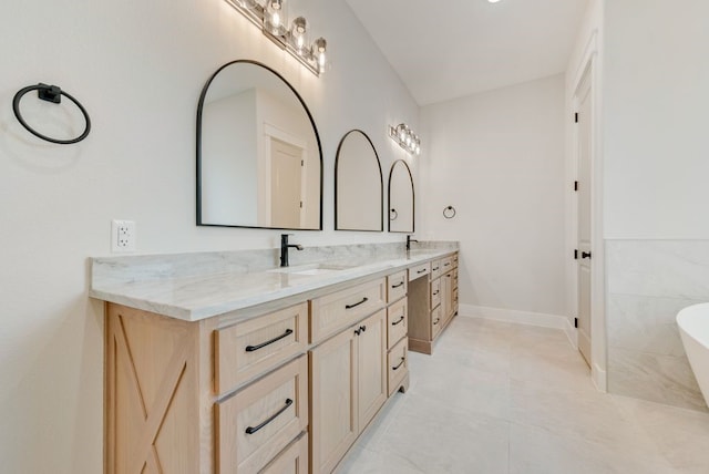 full bathroom with double vanity, a freestanding tub, tile patterned flooring, and baseboards