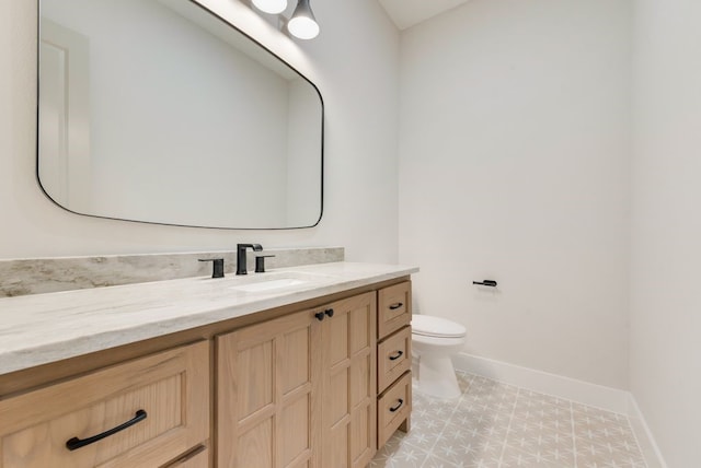 bathroom featuring baseboards, vanity, toilet, and tile patterned floors
