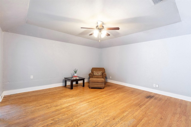 unfurnished room with ceiling fan, wood finished floors, baseboards, and a raised ceiling