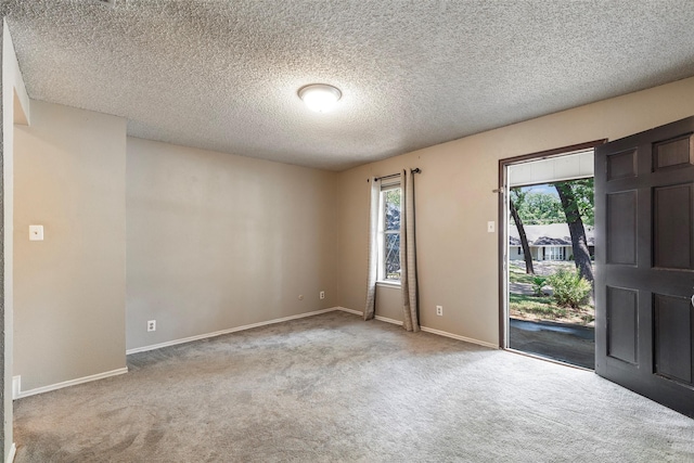 empty room featuring carpet flooring, a textured ceiling, and baseboards