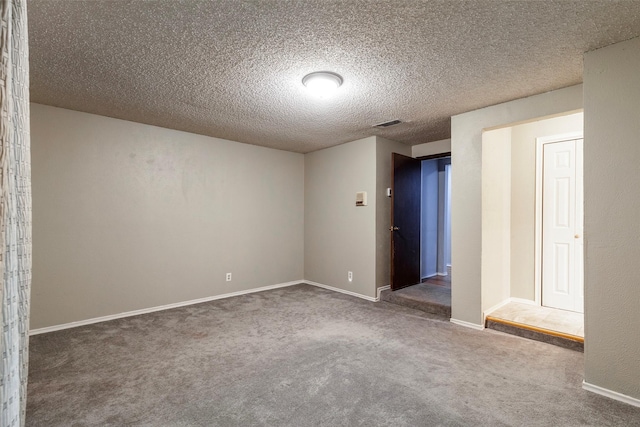 carpeted spare room featuring a textured ceiling and baseboards