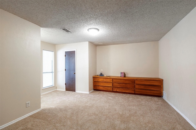bedroom with light colored carpet, baseboards, and a textured ceiling