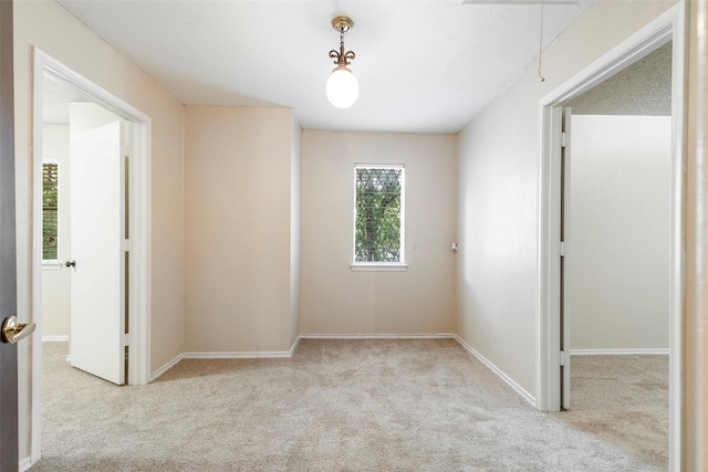 carpeted empty room featuring attic access and baseboards