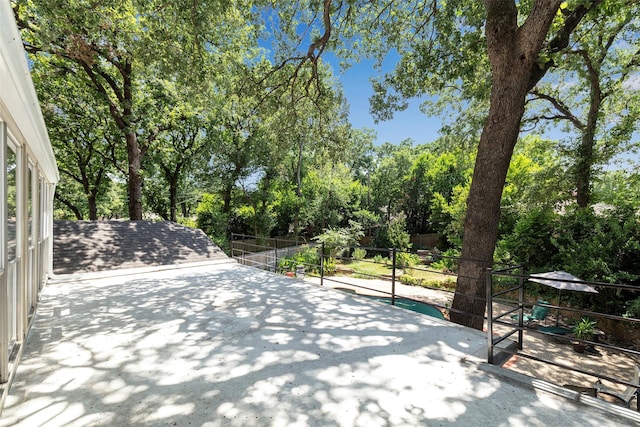 view of patio featuring view of scattered trees and fence
