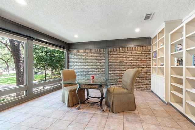 dining space with plenty of natural light, light tile patterned floors, a textured ceiling, brick wall, and built in features